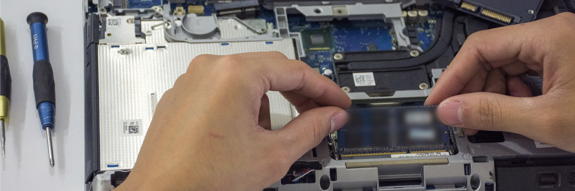 Mãos abrindo um notebook com chave de precisão para trocar uma peça